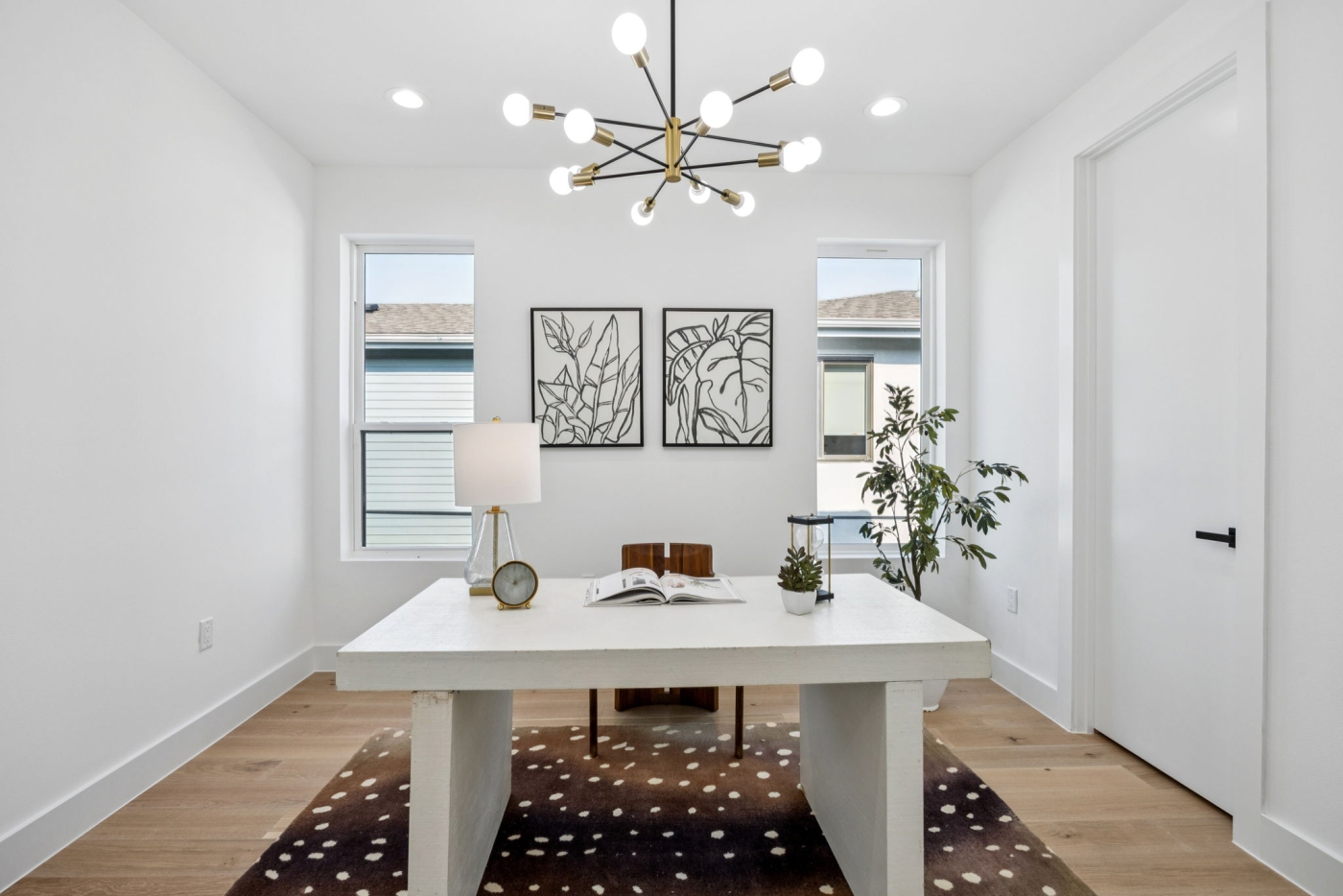 An office with a sleek white desk and neutral toned rug